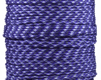 May include: A spool of blue, white, and gray paracord. The cord is tightly wound, creating a textured surface. The color pattern is a repeating design of small, interwoven sections. The spool is on a gray cardboard base.