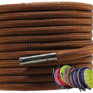 May include: A close-up of a spool of brown shoelaces with metal aglets. The shoelaces are coiled neatly and the aglets are visible at the end of the spool.