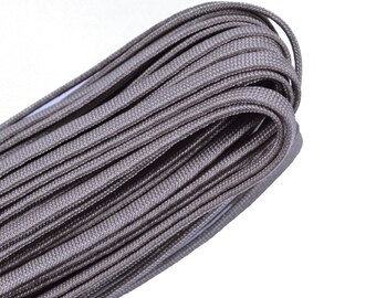 May include: A close-up of a spool of gray paracord, a type of strong nylon rope often used for crafting and outdoor activities.