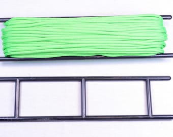 May include: A green paracord spool on a black plastic spool holder. The spool is full of paracord.