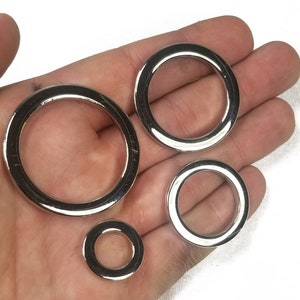 K&ouml;nnte beinhalten: Vier silberne Metallringe in verschiedenen Gr&ouml;&szlig;en. Die Ringe sind glatt und gl&auml;nzend.