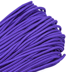 Puede incluir: Primer plano de un carrete de paracord morado. El paracord está enrollado apretado y tiene una textura lisa.