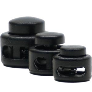 May include: Three black plastic cord locks of different sizes. The cord locks have a spring mechanism and are used for securing cords or straps.