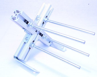 May include: A silver metal bracket with four silver metal rods attached to it. The bracket is made of aluminum and has a silver finish. The rods are attached to the bracket with screws and nuts.