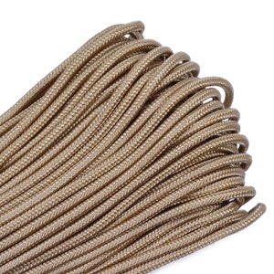 May include: A close-up of a spool of tan paracord, a type of strong nylon rope often used for crafting and survival.