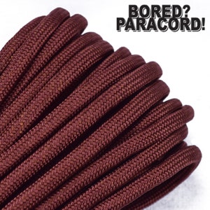 May include: Close-up of a spool of maroon paracord. The paracord is tightly wound and has a textured surface. The text "BORED? PARACORD!" is visible in the upper right corner of the image.
