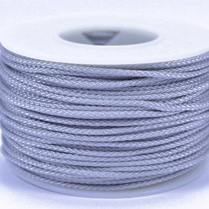 May include: A spool of silver gray cord, wound tightly on a white plastic bobbin.