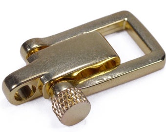 May include: A gold-toned metal clasp with a rectangular frame and a small, threaded knob. The clasp has a smooth, polished finish and a slightly worn appearance.