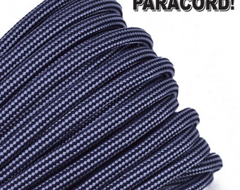 May include: Close-up of a coil of dark blue paracord with a black and white checkered pattern. The paracord is a type of rope used for crafting and survival.