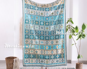 May include: A blue and white throw blanket with a geometric pattern. The blanket has a fringe border and is made of cotton.