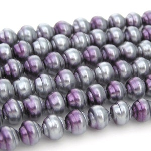 May include: A strand of purple and silver iridescent glass beads. The beads are oval shaped and have a smooth, glossy finish.