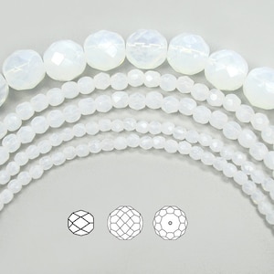 May include: A variety of white faceted glass beads in different sizes. The beads are arranged in a semi-circle with the largest beads at the top and the smallest beads at the bottom. The beads are all faceted and have a clear, iridescent finish.
