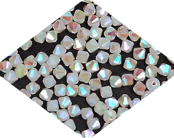 May include: A close-up view of iridescent white glass beads. The beads are faceted and have a pointed shape. The beads are scattered on a black surface.
