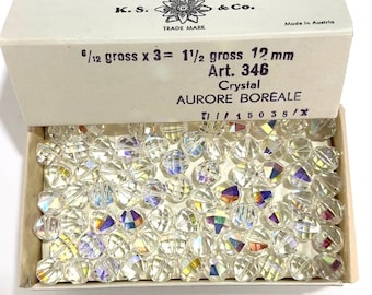 May include: A box of clear glass beads with iridescent rainbow colors. The box is labeled "K.S. & Co. Trade Mark" and "Made in Austria". The beads are 12 mm in size and are labeled "Art. 346 Crystal Aurore Boreale".