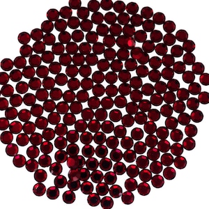 May include: A close-up of a large quantity of small, round, red rhinestones. The rhinestones are arranged in a circular pattern.