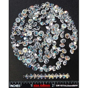 May include: A large quantity of clear glass beads with iridescent rainbow facets. The beads are 4mm in size and are arranged in a circle on a black surface. A ruler is visible at the bottom of the image with the text "size 4x5mm" and "CRYSTALSandBFF".