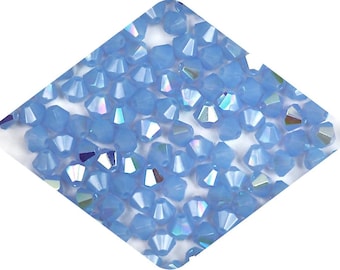 May include: A close-up view of a pile of light blue iridescent glass beads. The beads are faceted and have a shimmery finish.