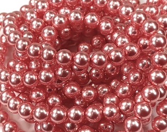 May include: A strand of pink pearl beads. The beads are round and have a smooth, glossy finish.