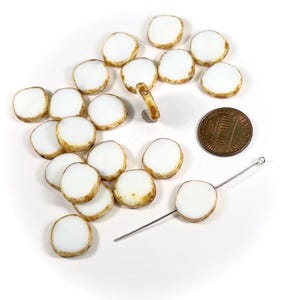 May include: A collection of white glass beads with a brown rim. The beads are approximately the size of a US penny.