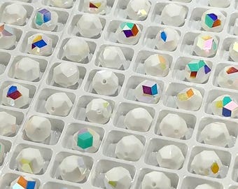 May include: A tray filled with white, faceted beads. Some beads have a clear, iridescent finish, reflecting multiple colors. The beads are arranged in a grid pattern within individual compartments, suggesting organized storage or display for crafting or jewelry making.