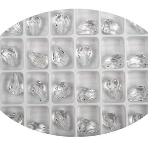 May include: A clear plastic container filled with clear teardrop-shaped crystal beads.