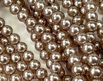 May include: A strand of round, iridescent, light brown pearl beads. The beads are smooth and have a high gloss finish.