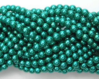 May include: A close-up of a collection of teal-colored, round beads. The beads have a glossy, reflective surface and are tightly packed together. The beads are likely used for jewelry making or other craft projects.