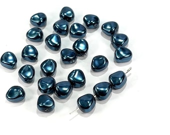 May include: A collection of dark teal, irregular-shaped beads with a glossy finish. Some beads are strung on a thin wire. The beads are scattered on a white surface, creating a visually appealing arrangement. These beads are suitable for jewelry making.