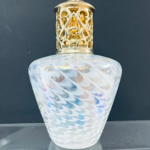 May include: A white iridescent glass oil diffuser bottle with a gold metal cage top. The bottle has a swirling pattern.