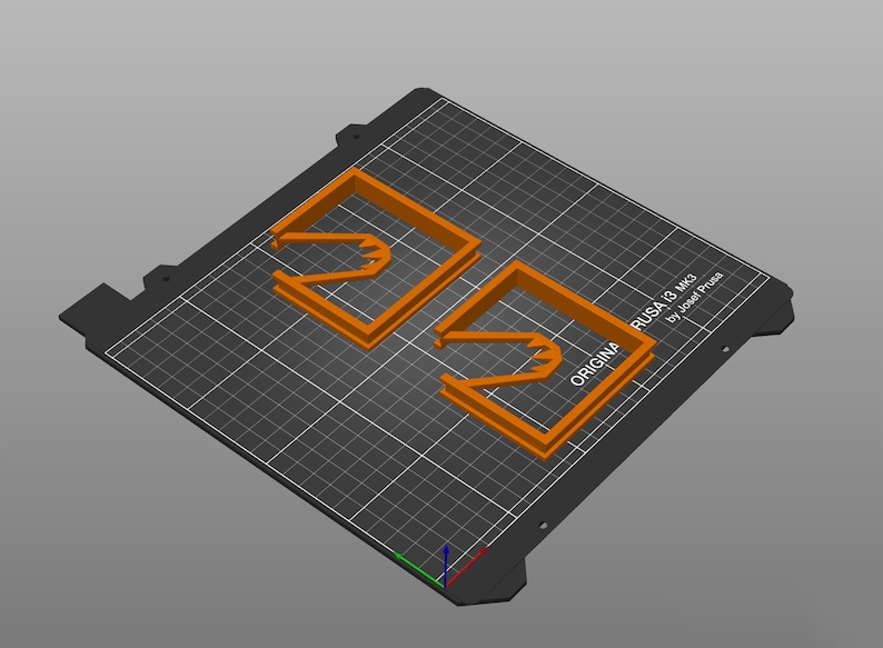 以下が含まれることがあります： 黒いテクスチャ加工された表面に、オレンジ色の3Dプリントされたオブジェクトが2つあります。オブジェクトは、中央に切り抜きのある正方形の形をしています。表面には「ORIGINAL PRUSA I3 MK3 by Josef Prusa」というテキストが表示されています。