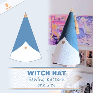 May include: A cone-shaped witch hat featuring a dark blue fabric upper section and a white textured fabric lower section. A gold-colored tassel hangs from the pointed top, and a small circular gold-colored metal embellishment is centered on the front.