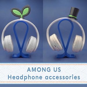 Op de afbeelding: Twee blauwe koptelefoonstandaards met verschillende decoratieve toppers. De ene standaard heeft een groene planten-topper en de andere heeft een zwarte hoge hoed-topper. De standaards zijn ontworpen om koptelefoons te houden.
