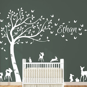 Op de afbeelding: Witte wanddecoratie met een boom met vlinders, herten en konijnen. De naam "Ethan" staat op de muur.