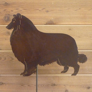 May include: A metal silhouette of a Collie dog, painted in a rusty brown color. The silhouette is mounted on a metal stake.