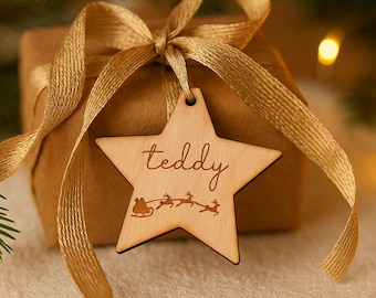 May include: A wrapped gift with a gold ribbon and a wooden star-shaped tag. The tag is engraved with the word "teddy" and a sleigh with reindeer. The gift is wrapped in brown paper.