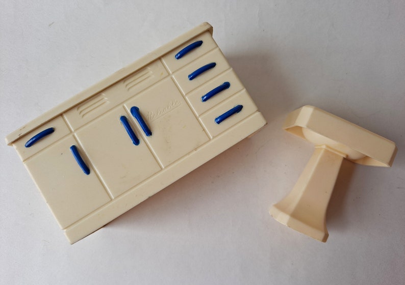 May include: A white plastic toy kitchen sink and cabinet set with blue handles. The cabinet has the word "Beswick" printed on the front.