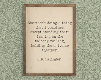 May include: A framed print featuring a quote by J.D. Salinger: "She wasn't doing a thing that I could see, except standing there leaning on the balcony railing, holding the universe together."