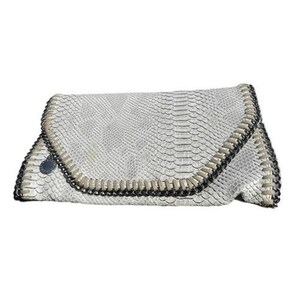 May include: A white clutch with a snakeskin pattern. The flap is outlined with a silver chain and black trim. The bag is closed with a silver button.