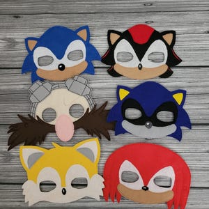 Peut inclure: Six masques en feutre représentant des personnages de la franchise de jeux vidéo Sonic the Hedgehog. Les masques sont bleus, rouges, jaunes, gris et noirs.