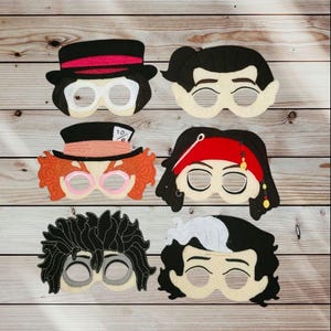May include: A set of six felt character masks featuring various hairstyles and headwear, including a black top hat, a Mad Hatter hat with a 10/6 tag, a red bandana, and distinct hair textures in black, orange, and white, all with eye cutouts.