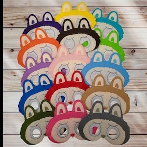 May include: A collection of colorful felt bunny masks in various shades, including blue, pink, orange, and green. Each mask features large eyes and upright ears, perfect for costume parties or imaginative play.