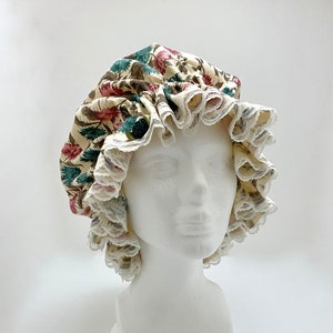 May include: A white and cream floral print shower cap with a white lace trim.