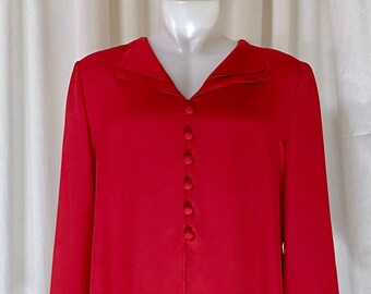 May include: A red button-up blouse with a layered ruffle hem. The blouse has a v-neck and long sleeves.