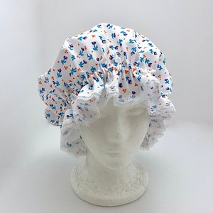 May include: White shower cap with a blue and orange floral print and white lace trim.