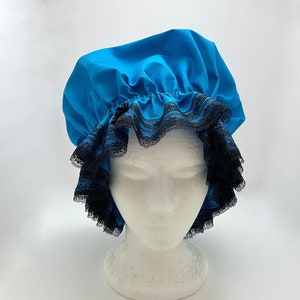 May include: A bright blue shower cap with black lace trim. The cap is gathered at the top and has a small black bow.
