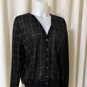 May include: Black and gold checkered cardigan with a v-neck and button closure.