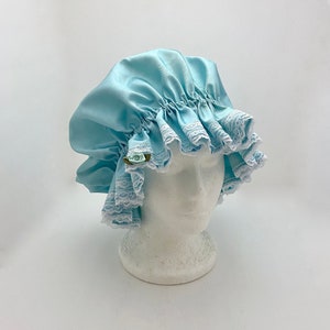 May include: A light blue satin shower cap with white lace trim and a small blue flower embellishment.