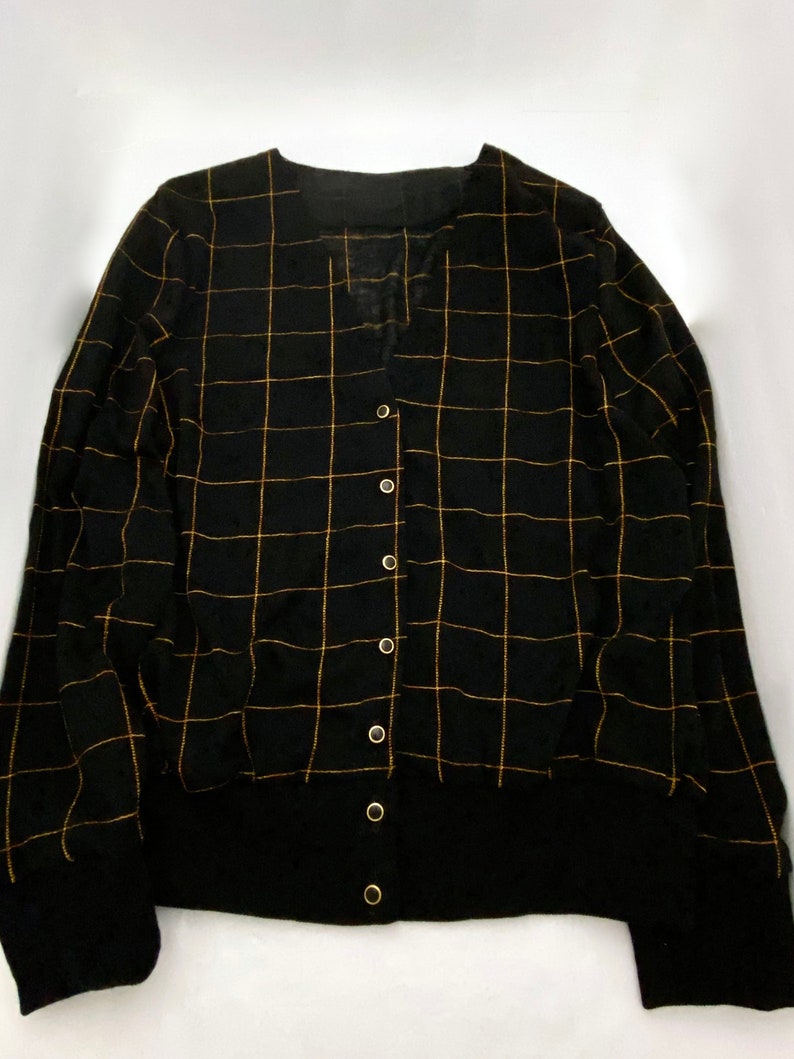 May include: Black cardigan with a gold grid pattern and button closure.