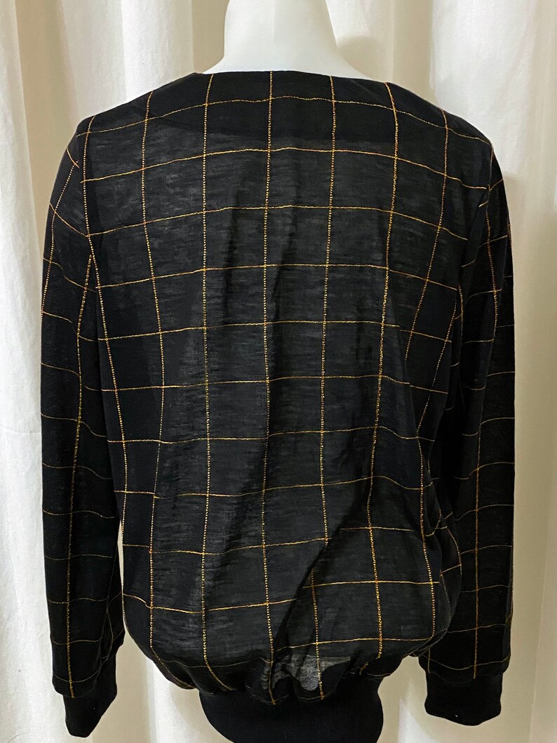 May include: Black long-sleeved shirt with a gold grid pattern.