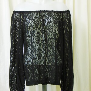 May include: Black off-the-shoulder lace top with long sleeves and purple ribbon trim at the cuffs.